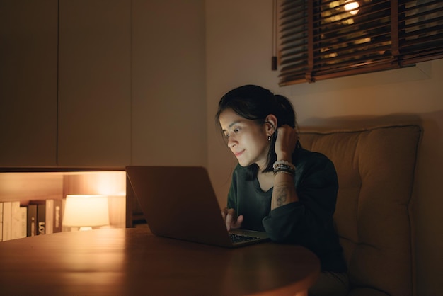 Mujer usando portátil por la noche mujer joven usando computadora en casa