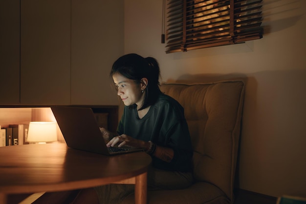 Mujer usando portátil por la noche mujer joven usando computadora en casa