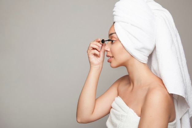 Foto mujer usando el rizador de pestañas tras ducharse