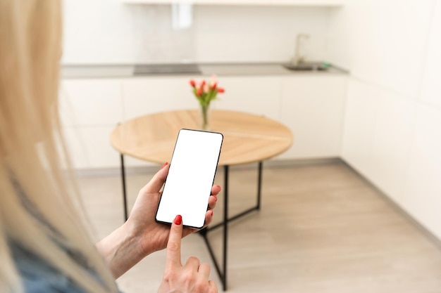Mujer usando smartohone en casa inteligente, pantalla vacía.