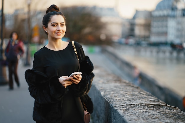 mujer usando su teléfono celular mientras camina por las calles de París Francia