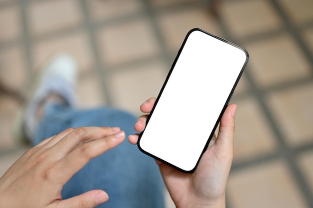 Una mujer usando su teléfono inteligente mientras se relaja al aire libre Maqueta de pantalla blanca de teléfono inteligente