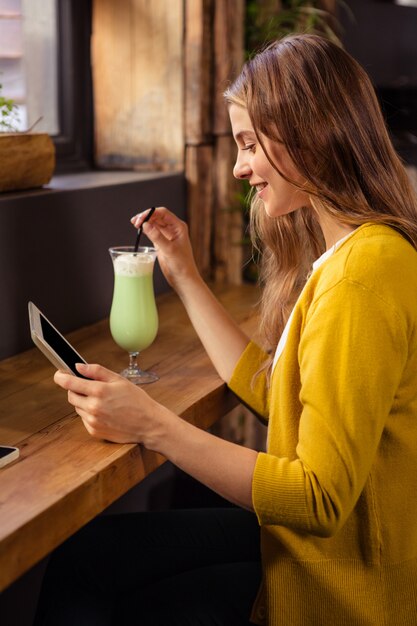 Foto mujer usando tableta y bebiendo batido