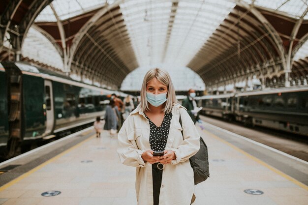 Mujer usando un teléfono en una estación de tren