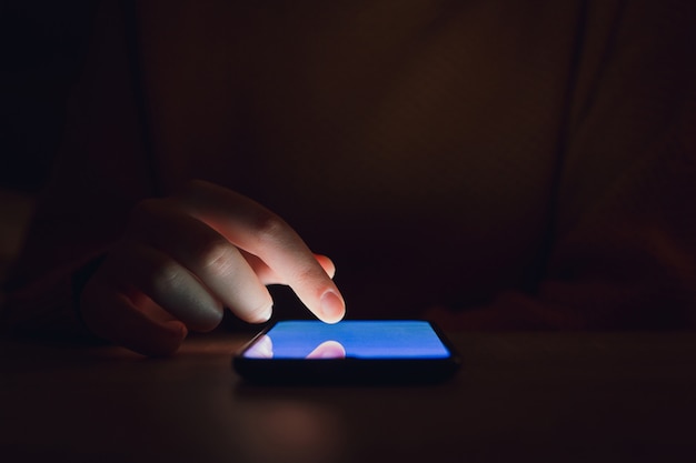 Una mujer usando un teléfono inteligente en la oscuridad