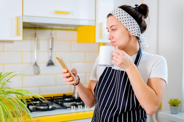 Foto mujer usando teléfono inteligente y tomando café en el concepto de cocina feliz mañana de ocio