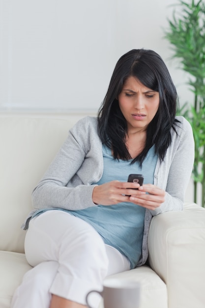 Mujer usando un teléfono mientras se relaja en un sofá