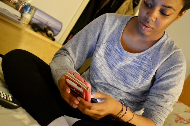 Foto mujer usando el teléfono mientras está sentada en la cama