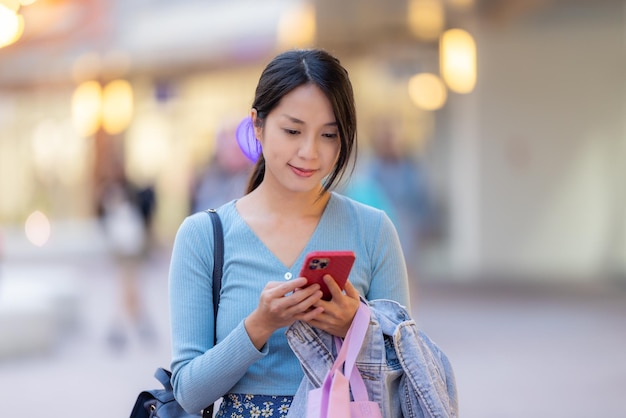 Mujer usando teléfono móvil en el área comercial