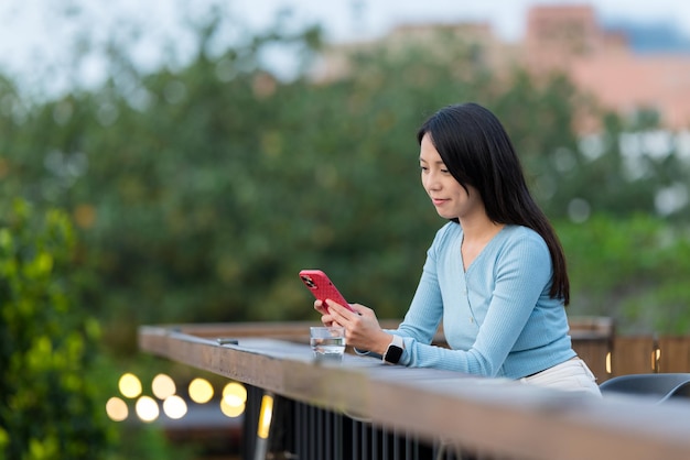 Mujer usando el teléfono móvil en una cafetería al aire libre