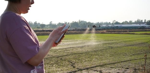 Mujer usando un teléfono móvil en una granja rodeada por el control de la granja Agricultura Petrol Drone Sprayer