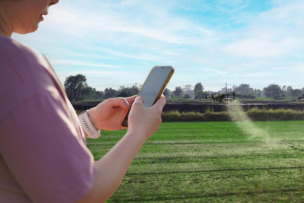 Mujer usando un teléfono móvil en una granja rodeada por el control de la granja Agricultura Petrol Drone Sprayer