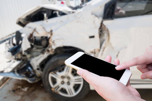 Mujer usando un teléfono móvil inteligente tomando fotos del daño del accidente automovilístico para el seguro