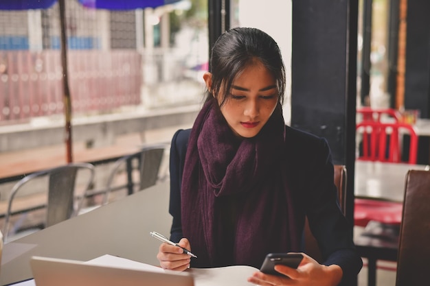 Mujer usando teléfono móvil mientras está sentada en una cafetería