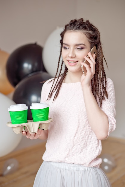 Foto mujer usando un teléfono y sosteniendo una taza de café de papel