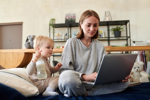 mujer, usar la computadora portátil, mientras, sentado, con, bebé