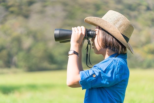 Mujer usar sombrero y mantener binocular en campo de hierba