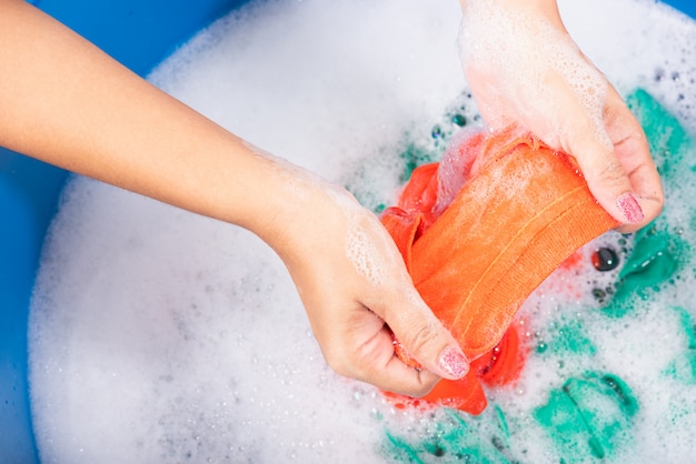 Mujer use manos lavando ropa de color en la cuenca