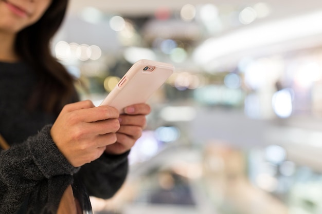 Mujer uso de teléfono móvil en centro comercial