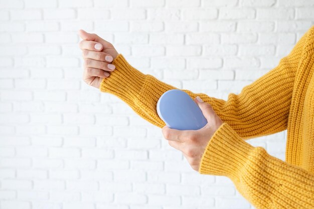 Foto mujer utiliza una máquina para quitar pellets y bobinas de la ropa y la tela en suéter amarillo