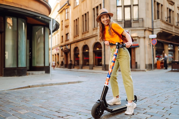 Mujer de vacaciones divirtiéndose conduciendo scooter eléctrico por la ciudad Concepto de transporte ecológico