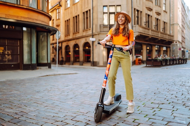 Mujer de vacaciones divirtiéndose conduciendo un scooter eléctrico por la ciudad Concepto de transporte ecológico