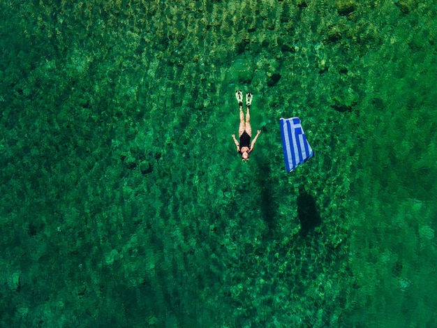 Foto mujer de vacaciones de verano en grecia flotando en el agua con espacio de copia de bandera