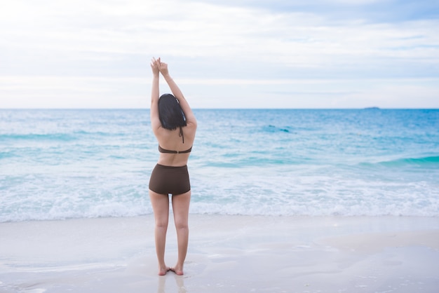 Mujer de vacaciones de verano de playa en el concepto de libertad feliz con los brazos levantados en la felicidad.