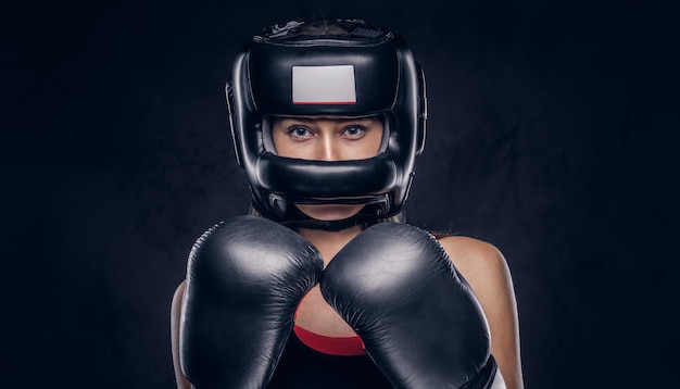 La mujer valiente está lista para pelear, lleva guantes de boxeador y casco protector.