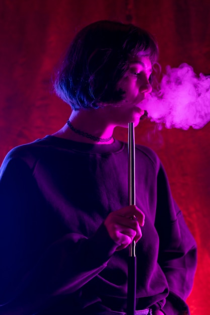 Foto mujer vaping de una pipa de agua en interiores