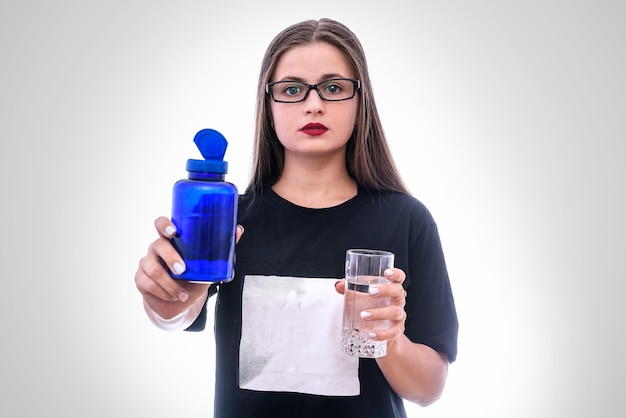 Mujer con vaso de agua y pastillas en botella aislada