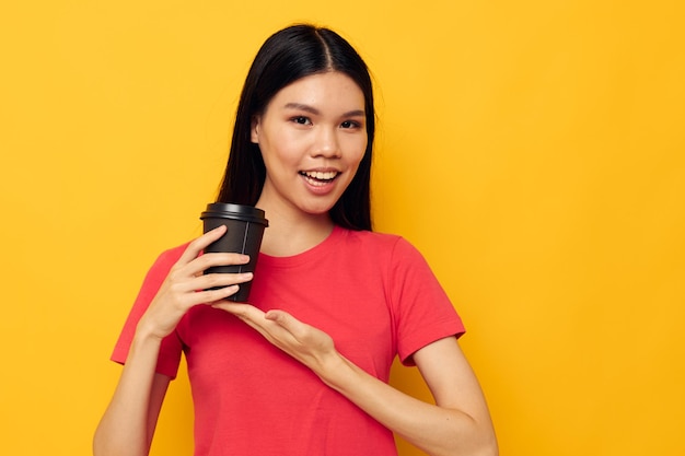 Mujer en un vaso de camiseta roja con un fondo amarillo de bebida