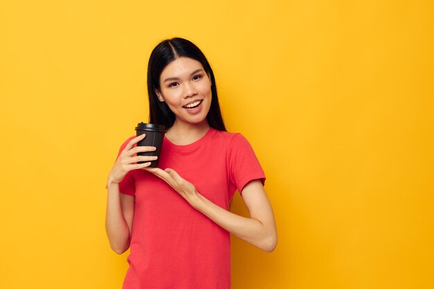 Mujer en un vaso de camiseta roja con un fondo amarillo de bebida