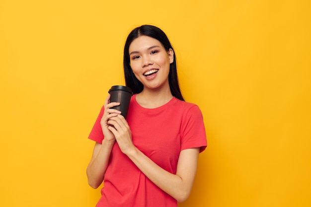 Mujer en un vaso de camiseta roja con un fondo amarillo de bebida