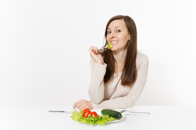 Mujer vegana en la mesa con ensalada de hojas de lechuga, verduras en un plato aislado sobre fondo blanco. Nutrición adecuada, comida vegetariana, concepto de dieta de estilo de vida saludable. Área de publicidad con espacio de copia.