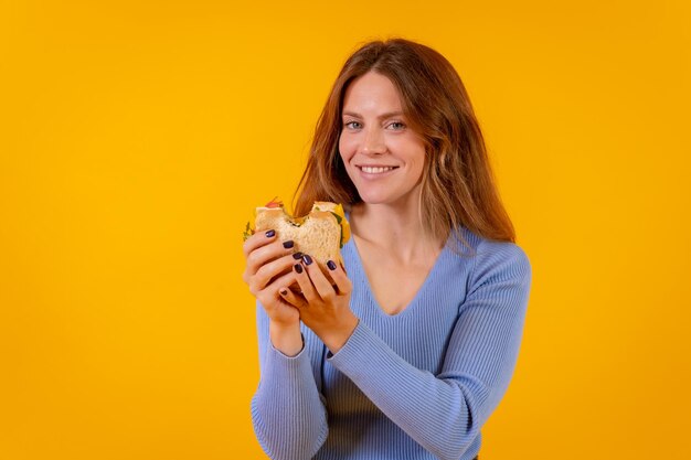 Mujer vegetariana comiendo un sándwich en un fondo amarillo comida vegetariana saludable