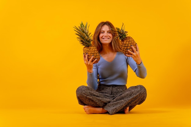 Mujer vegetariana sonriendo con una piña cortada sentada en un concepto de vida saludable y fruta tropical