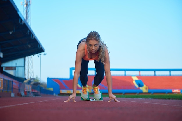 mujer velocista dejando bloques de salida en la pista de atletismo. Vista lateral. comienzo explosivo