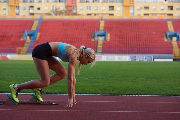 mujer velocista dejando bloques de salida en la pista de atletismo. Vista lateral. comienzo explosivo