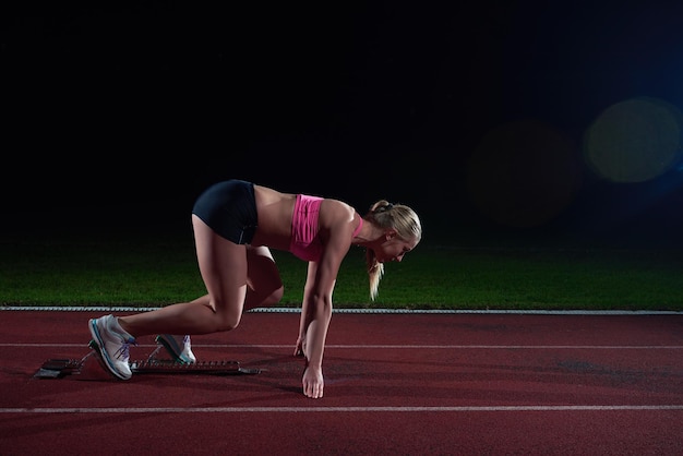 mujer velocista dejando bloques de salida en la pista de atletismo. Vista lateral. comienzo explosivo