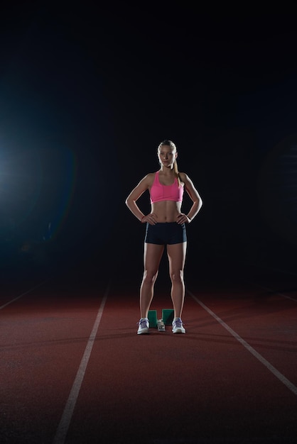 mujer velocista dejando bloques de salida en la pista de atletismo. Vista lateral. comienzo explosivo