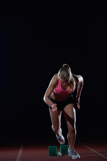 mujer velocista dejando bloques de salida en la pista de atletismo. Vista lateral. comienzo explosivo