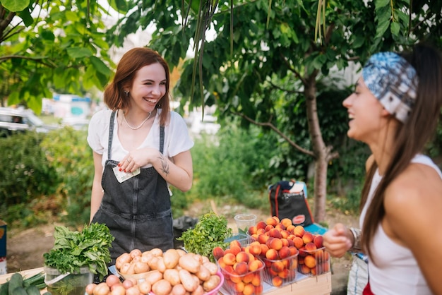 Mujer vendedora ofrece verduras frescas y orgánicas al mercado de agricultores.