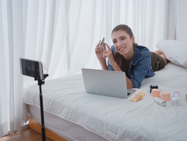 Mujer vendiendo cosméticos en línea con computadora, haciendo negocios en su casa