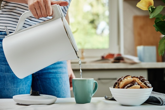 Mujer vertiendo agua de la tetera para preparar té