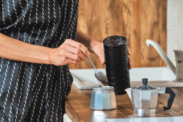 Mujer vertiendo café molido en la cafetera