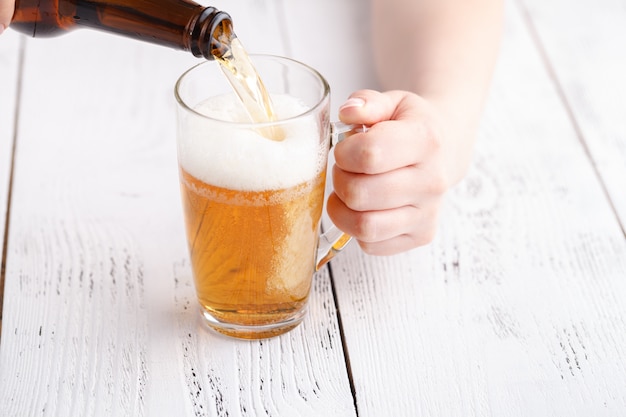 Mujer vertiendo cerveza en la taza de cristal, relajarse concepto