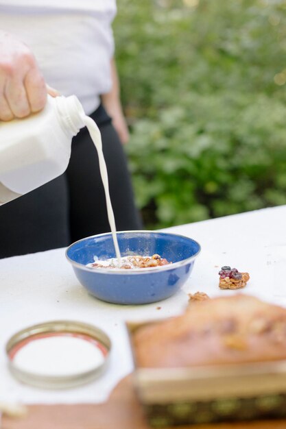 Mujer vertiendo leche fresca en un tazón de cereal