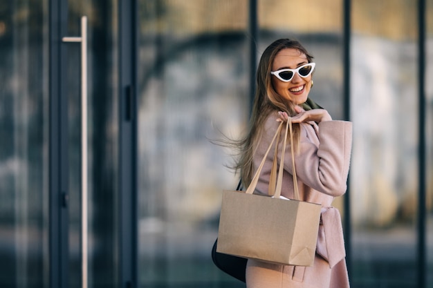 Una mujer vestida con un abrigo y gafas de sol sale de un centro comercial