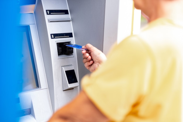 Mujer vestida de amarillo retirar dinero de la tarjeta de crédito en cajeros automáticos